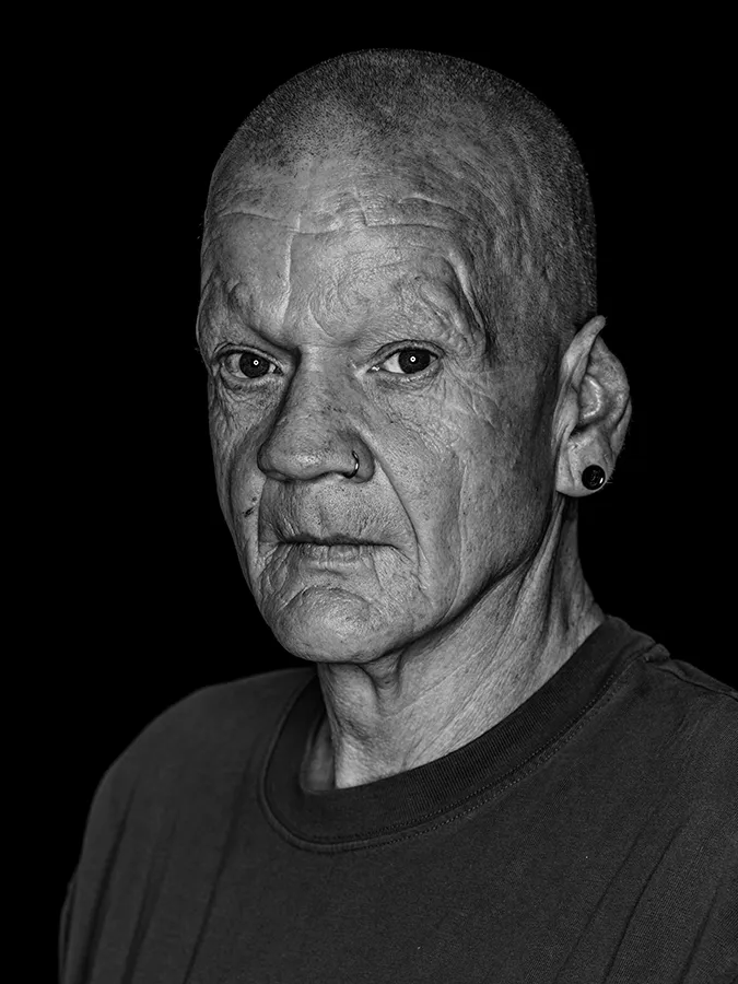 Klassisches Portrait aus der Serie Faces of St. Pauli in schwarz-weiss vor schwarzem Hintergrund von Peppi