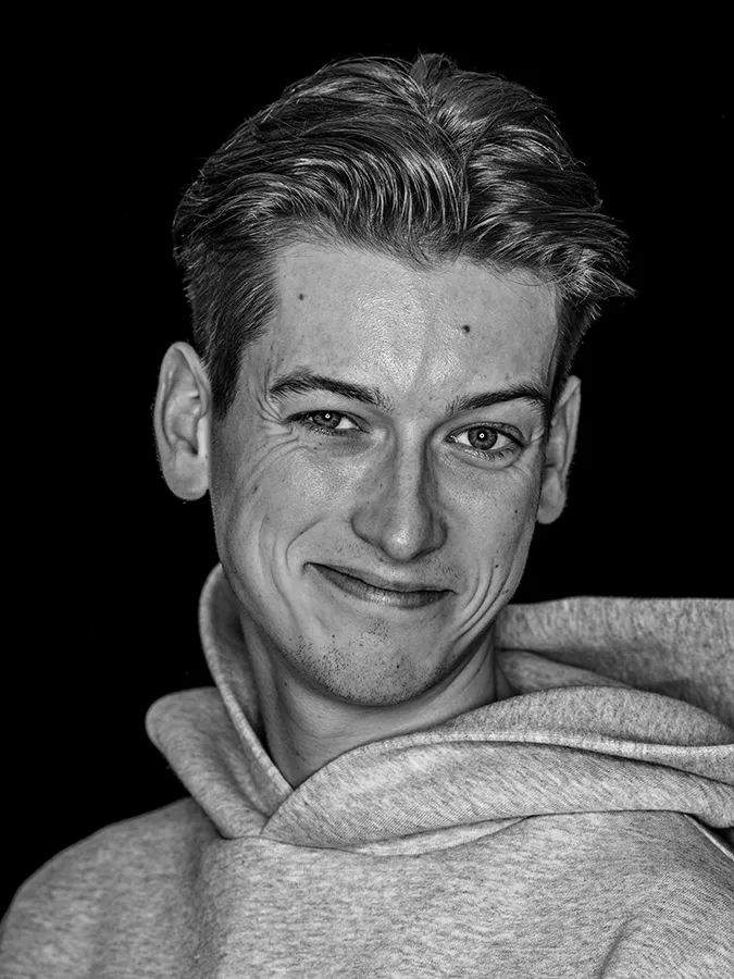 Klassisches Portrait aus der Serie Faces of St. Pauli in schwarz-weiss vor schwarzem Hintergrund von Tim Wittwer