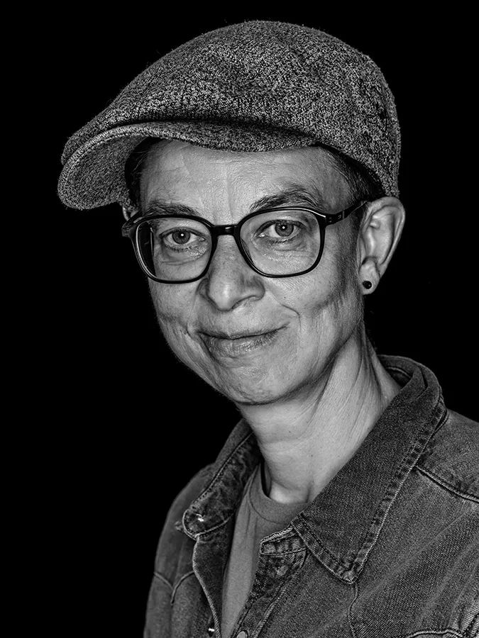 Klassisches Portrait aus der Serie Faces of St. Pauli in schwarz-weiss vor schwarzem Hintergrund von Tanja Rieckmann-Mekhchoun
